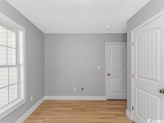 23 Gabe Pl, Pawleys Island, SC 29585 - unfurnished bedroom with multiple windows, light wood-style floors, and baseboards