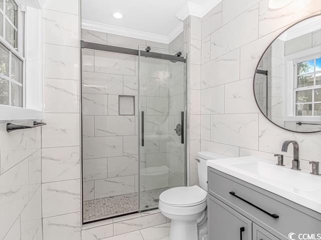 23 Gabe Pl, Pawleys Island, SC 29585 - bathroom featuring crown molding, marble look tiles, a shower stall, toilet, and tile walls