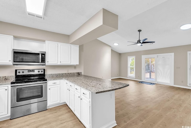 4339 Baldwin Ave Unit 4339, Little River, SC 29566 - kitchen with stainless steel appliances, a peninsula, ceiling fan, light wood-style floors, and white cabinetry