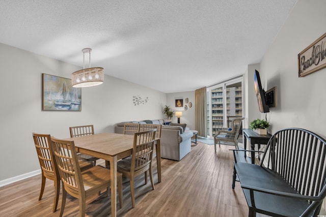 dining area with a textured ceiling, wood finished floors, and baseboards