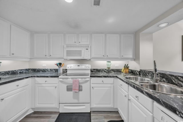 kitchen with white appliances, a sink, white cabinets, wood finished floors, and recessed lighting