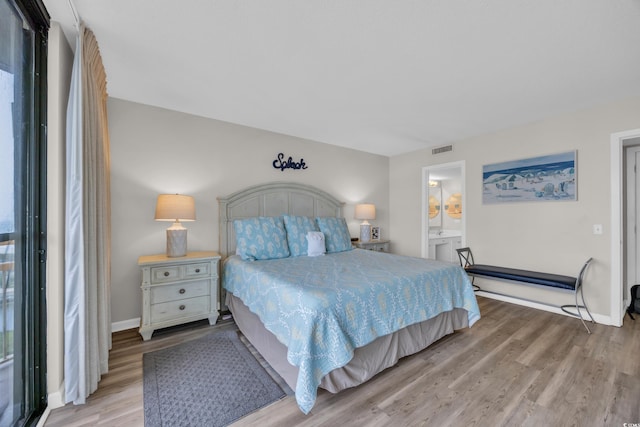 bedroom featuring light wood-style floors, baseboards, ensuite bathroom, and multiple windows
