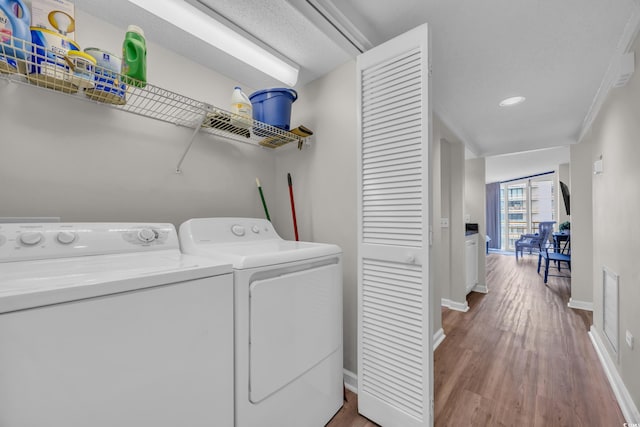 laundry area with washing machine and clothes dryer, wood finished floors, baseboards, and recessed lighting