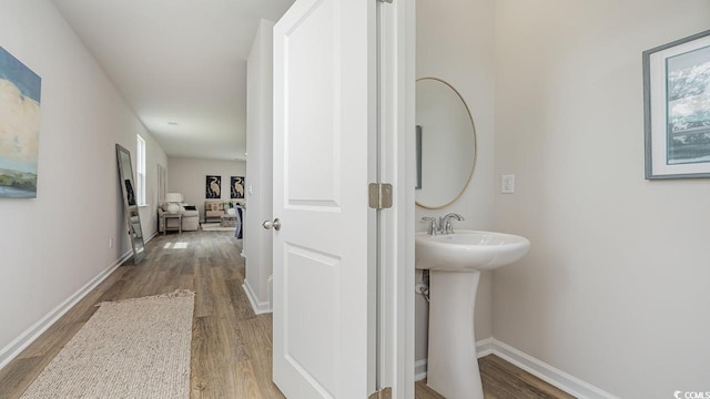 bathroom with wood finished floors, baseboards, and a sink