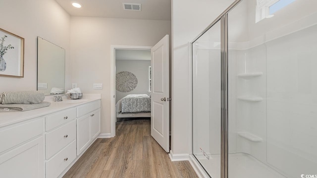 ensuite bathroom with wood finished floors, a stall shower, vanity, and recessed lighting