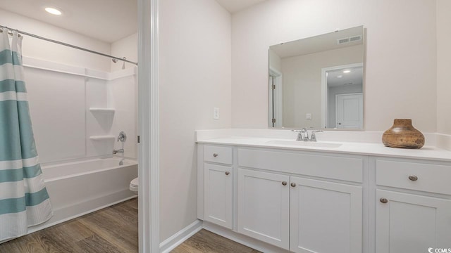 bathroom featuring wood finished floors, vanity, toilet, and shower / bathtub combination with curtain