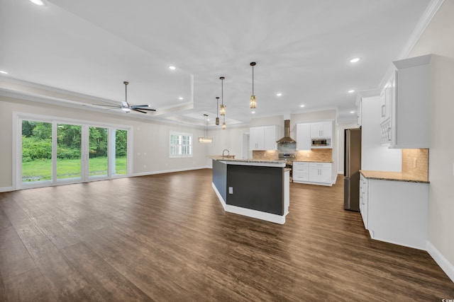 kitchen featuring stainless steel appliances, wall chimney range hood, ornamental molding, decorative backsplash, and dark wood-style floors