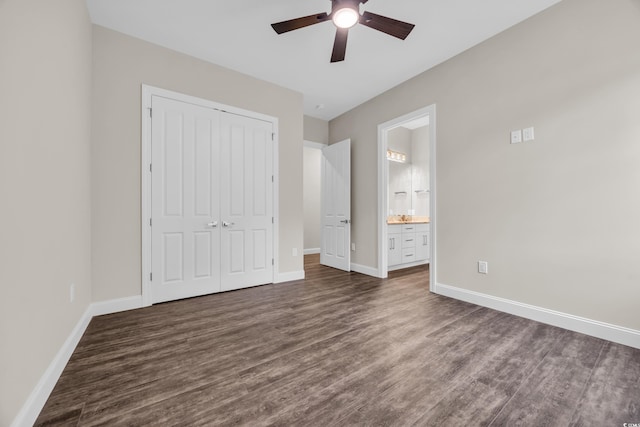 unfurnished bedroom featuring dark wood-style floors, baseboards, a closet, connected bathroom, and ceiling fan