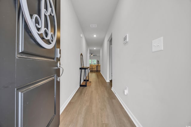 hall featuring light wood-type flooring, baseboards, and recessed lighting