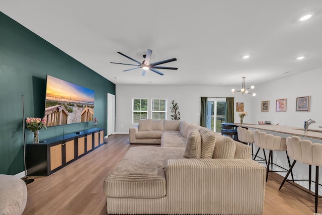 living area featuring a chandelier, wood finished floors, recessed lighting, a ceiling fan, and baseboards