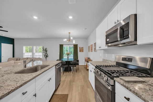 kitchen with appliances with stainless steel finishes, a sink, light wood-type flooring, a chandelier, and white cabinetry