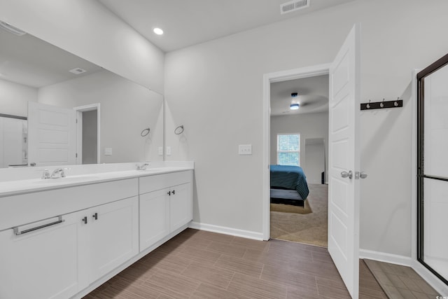 ensuite bathroom with baseboards, a shower with shower door, double vanity, and recessed lighting