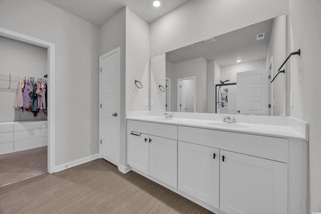 bathroom featuring double vanity, baseboards, a spacious closet, recessed lighting, and wood finished floors