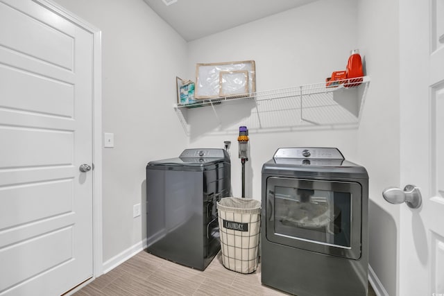 clothes washing area with washer and dryer and baseboards