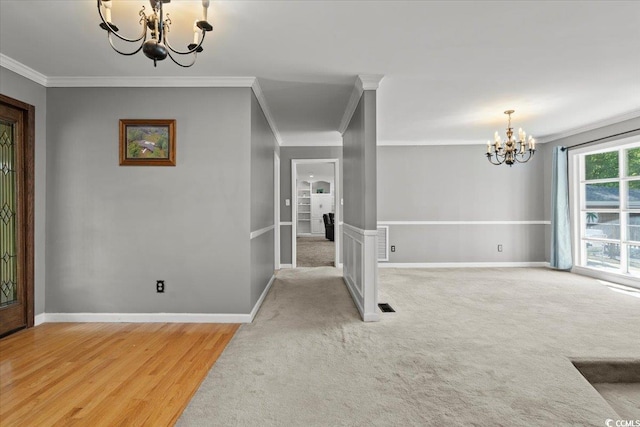 foyer featuring a chandelier, ornamental molding, baseboards, light wood-type flooring, and light carpet