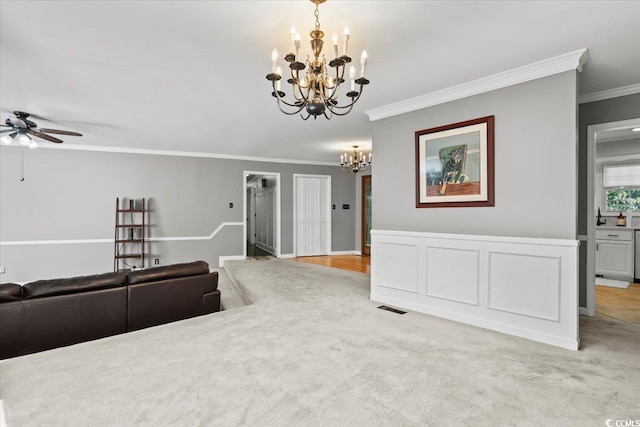 carpeted living area featuring a chandelier, ornamental molding, and a ceiling fan