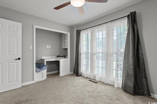 unfurnished bedroom with light colored carpet, a ceiling fan, and baseboards
