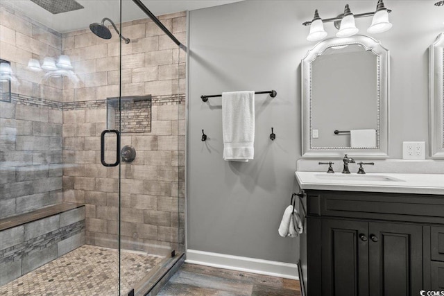 bathroom featuring a stall shower, baseboards, wood finished floors, and vanity
