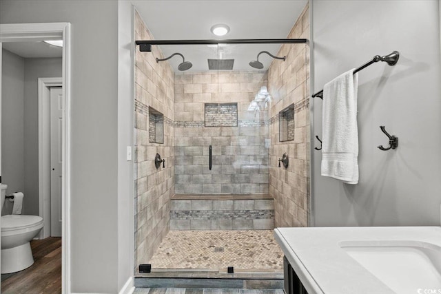 full bath featuring a stall shower, wood finished floors, toilet, and vanity