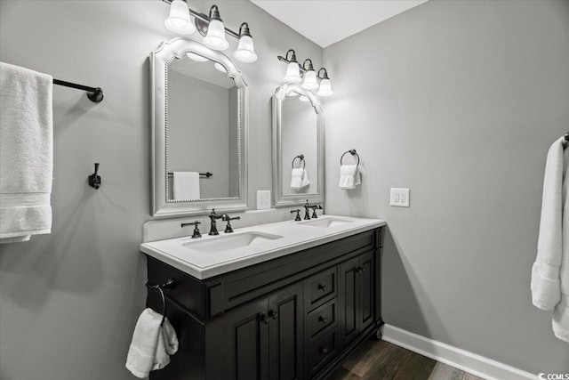 full bathroom with wood finished floors, double vanity, and baseboards