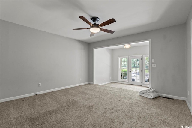 carpeted empty room with ceiling fan and baseboards