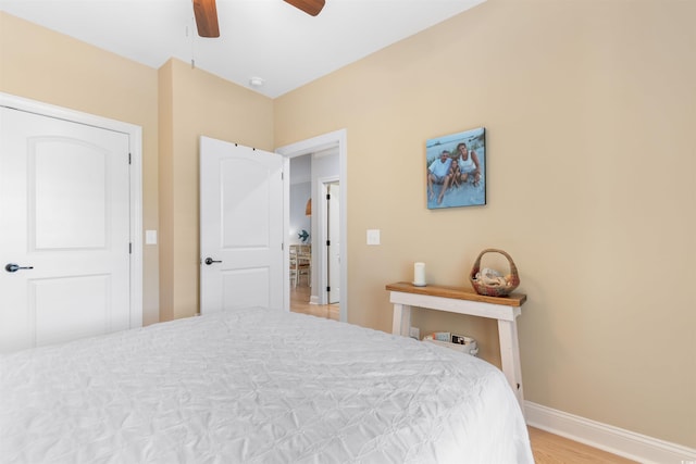 bedroom featuring baseboards, light wood-type flooring, and a ceiling fan