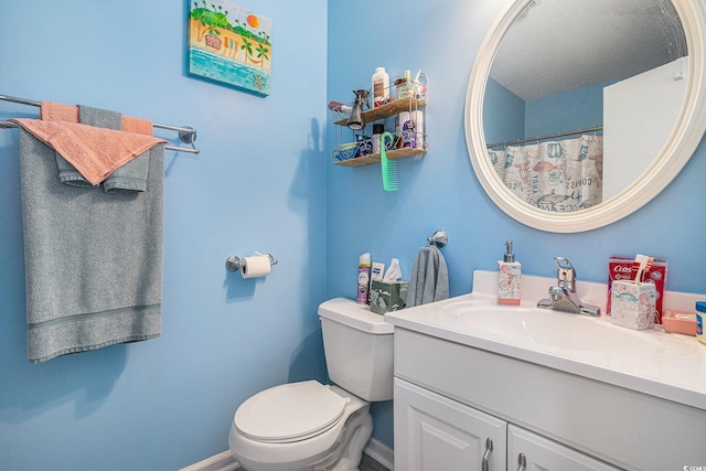 bathroom with toilet, vanity, and baseboards