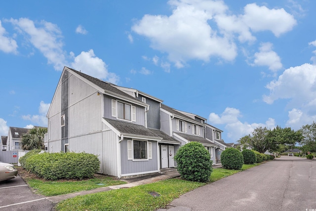view of front of property featuring a residential view, uncovered parking, and a shingled roof