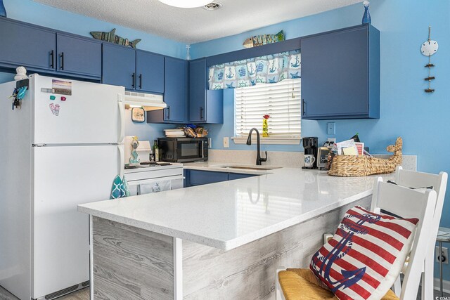 3700 Golf Colony Ln Unit 6J, Little River, SC 29566 - kitchen featuring white appliances, blue cabinets, a sink, under cabinet range hood, and a peninsula