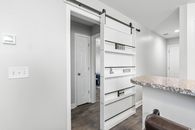 kitchen with dark wood-style flooring, a barn door, light countertops, baseboards, and white cabinetry