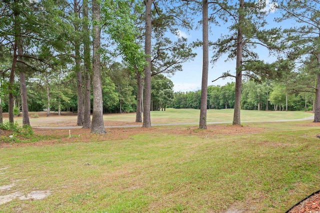 view of green lawn with view of wooded area