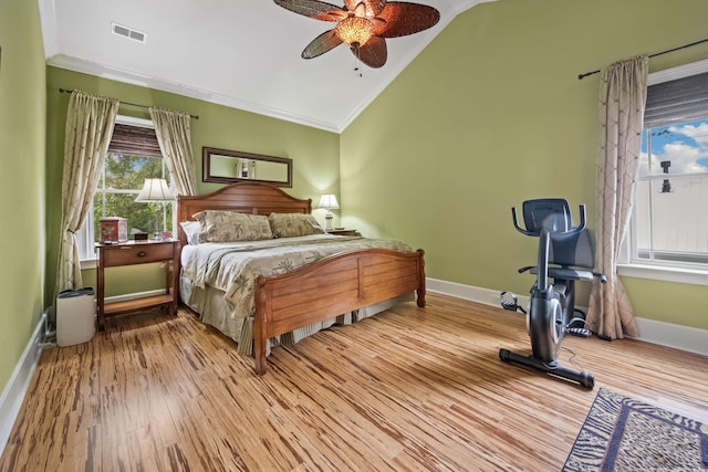 bedroom with vaulted ceiling, wood finished floors, baseboards, crown molding, and ceiling fan