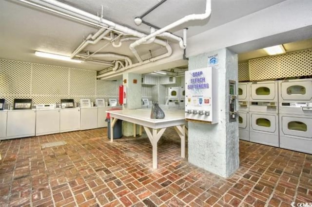 shared laundry with stacked washer and clothes dryer, brick flooring, and washing machine and dryer