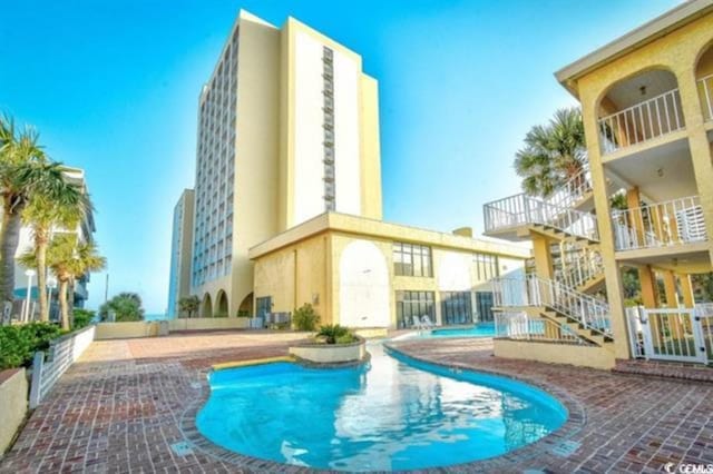 community pool featuring stairway and a patio area