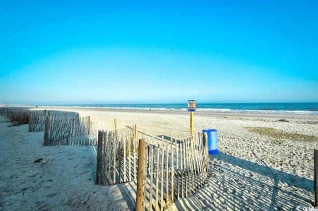 water view featuring local beach and fence
