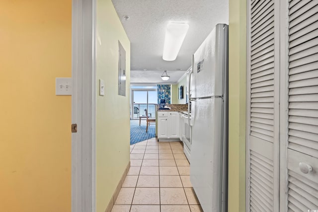 corridor with light tile patterned floors, a textured ceiling, electric panel, and baseboards