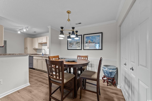 dining space with ornamental molding, light wood-style flooring, a chandelier, track lighting, and a textured ceiling