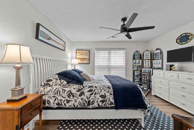 bedroom with wood finished floors, a textured ceiling, and ceiling fan