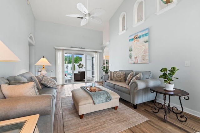 living area featuring high vaulted ceiling, a ceiling fan, wood finished floors, and baseboards