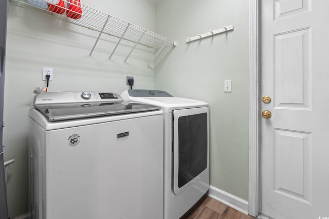 laundry room with washer and clothes dryer, dark wood-type flooring, and baseboards