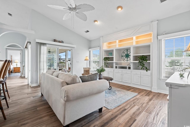 living room featuring ceiling fan, arched walkways, wood finished floors, high vaulted ceiling, and baseboards