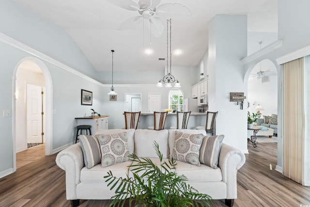 living room featuring a ceiling fan, wood finished floors, baseboards, arched walkways, and high vaulted ceiling