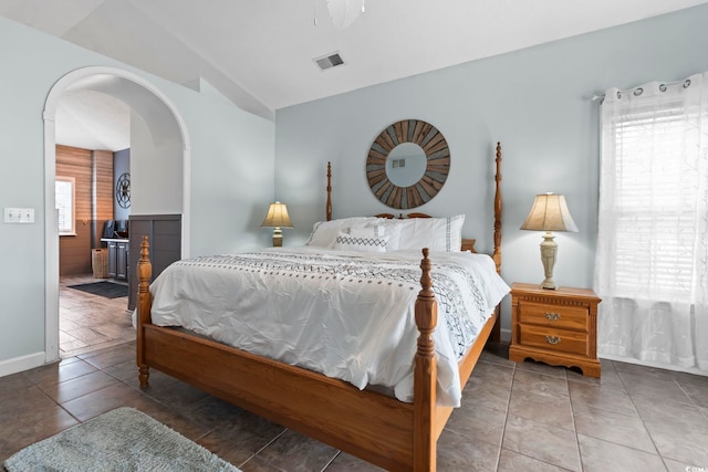 bedroom with vaulted ceiling, arched walkways, and baseboards