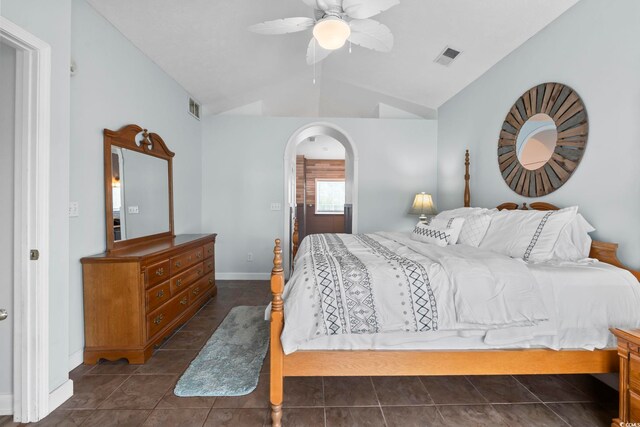 bedroom featuring vaulted ceiling, baseboards, arched walkways, a ceiling fan, and dark tile patterned flooring