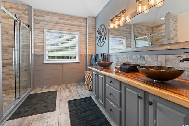 bathroom with a stall shower, double vanity, and wood finished floors