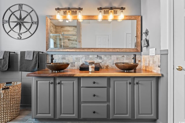 full bathroom with a shower stall, double vanity, and decorative backsplash