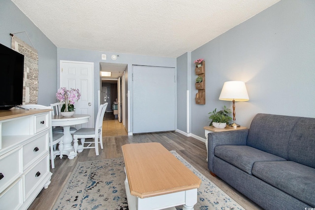 living area with wood finished floors, a textured ceiling, and baseboards
