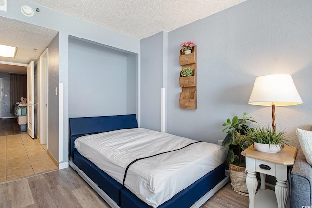 bedroom with a textured ceiling, wood finished floors, and a closet