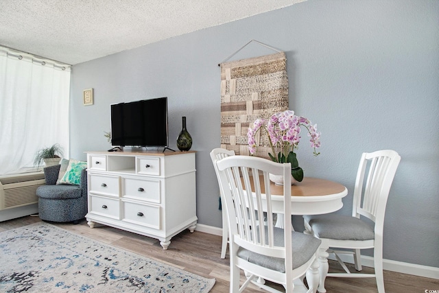 dining area featuring light wood-style floors, baseboards, and a textured ceiling
