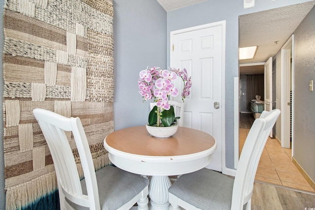 dining room featuring a textured ceiling, baseboards, and light tile patterned flooring
